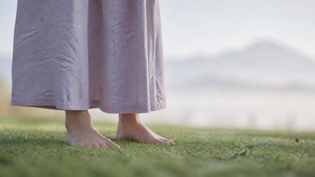 Pies descalzos sobre el pasto en la mañana, como imagen de volver al cuerpo y al presente